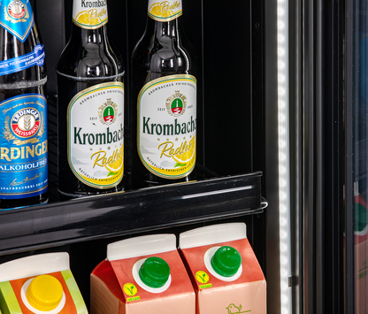 KBS Glastürkühlschrank 327 G Slim, Nahaufnahme von Krombacher Radler Bierflaschen und Saftkartons in der unteren Regalebene.