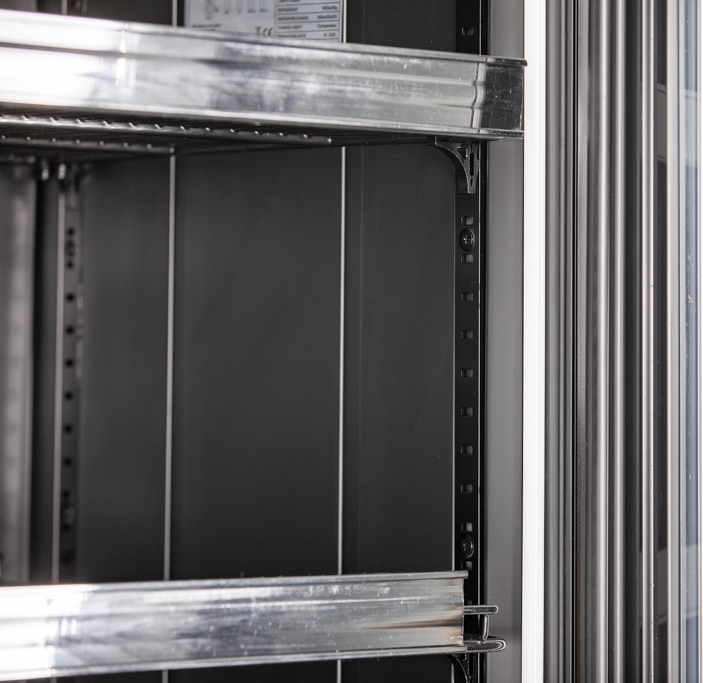 KBS Glastürkühlschrank 327 G Slim, Detailaufnahme des schwarzen Innenraums mit verstellbaren Metallböden und Türrahmen.