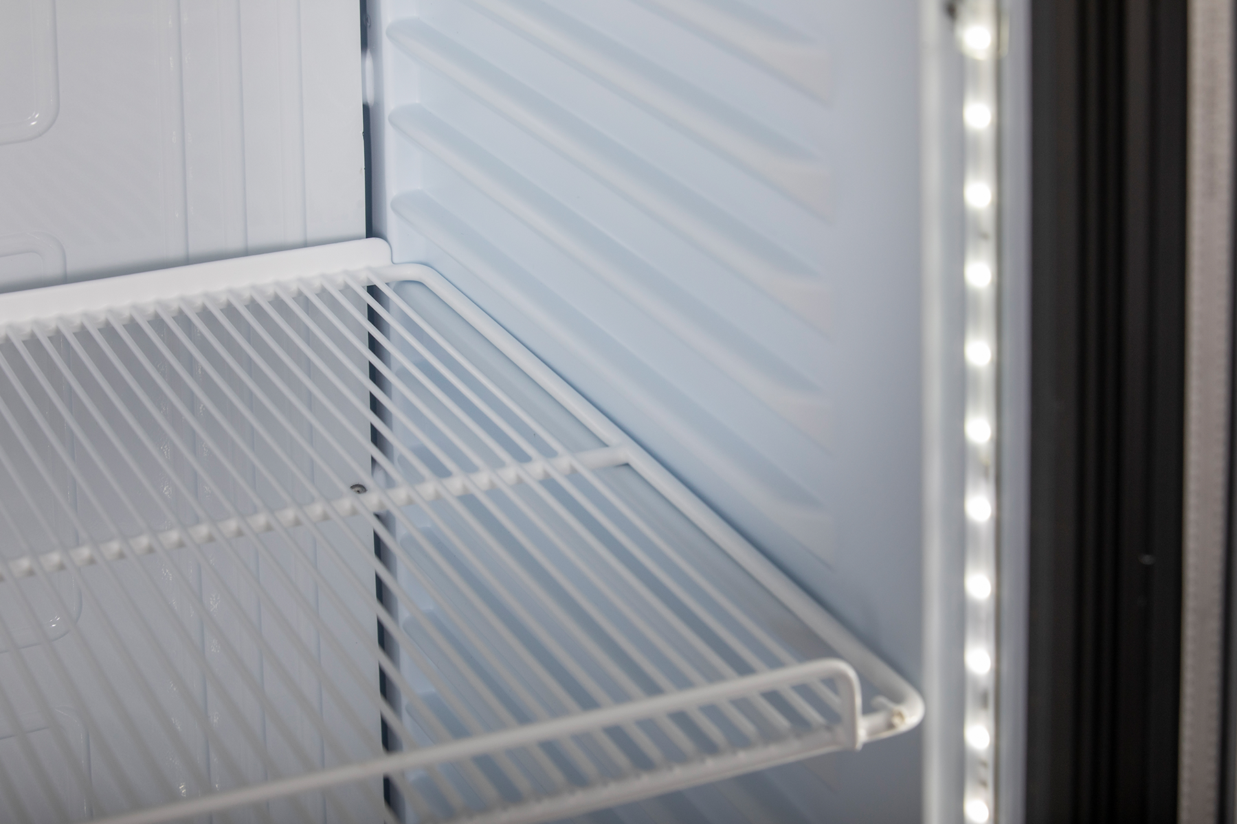KBS Glastürkühlschrank 375 GDU Innenansicht aus schräger Perspektive mit leerem weißen Gitterrost und seitlicher LED-Beleuchtung, geeignet für Gastronomie, Pizzeria oder Bäckerei.