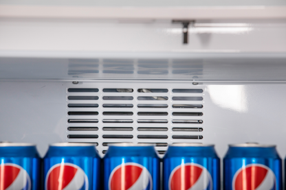 Detailansicht KBS Glastürkühlschrank 375 GDU Nahaufnahme des Lüftungsgitters im Innenraum oberhalb einer Reihe Pepsi-Dosen, sorgt für gleichmäßige Kaltluftverteilung.