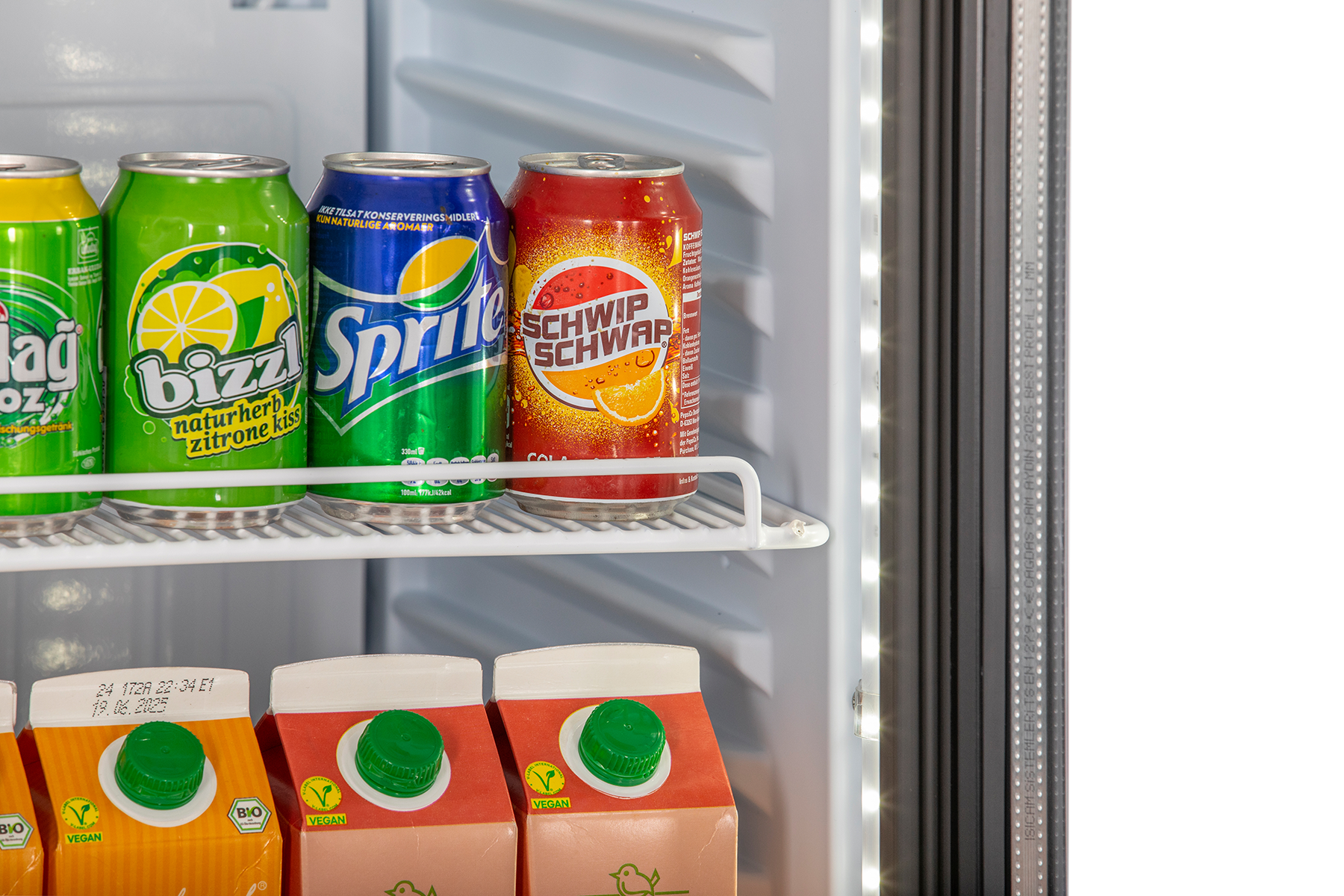 Detailansicht KBS Glastürkühlschrank 375 GDU Innenraum mit Getränkedosen Sprite, Bizzl und Schwip Schwap sowie darunterstehenden Saftkartons, Blick auf Türdichtung und LED-Beleuchtung.
