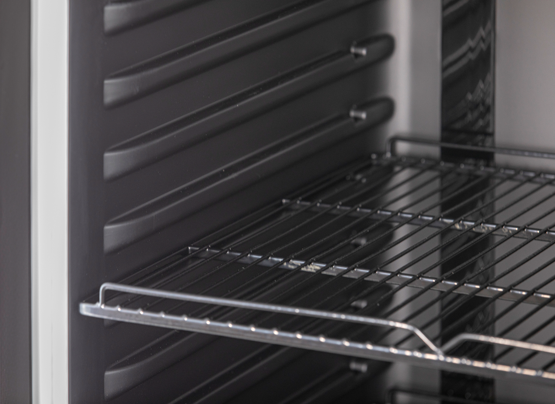 KBS Glastürkühlschrank 384 Detailaufnahme einer leeren schwarzen Innenwand mit stabilen Drahtgitterböden, für flexible Lagerung in Gastronomie und Handel.