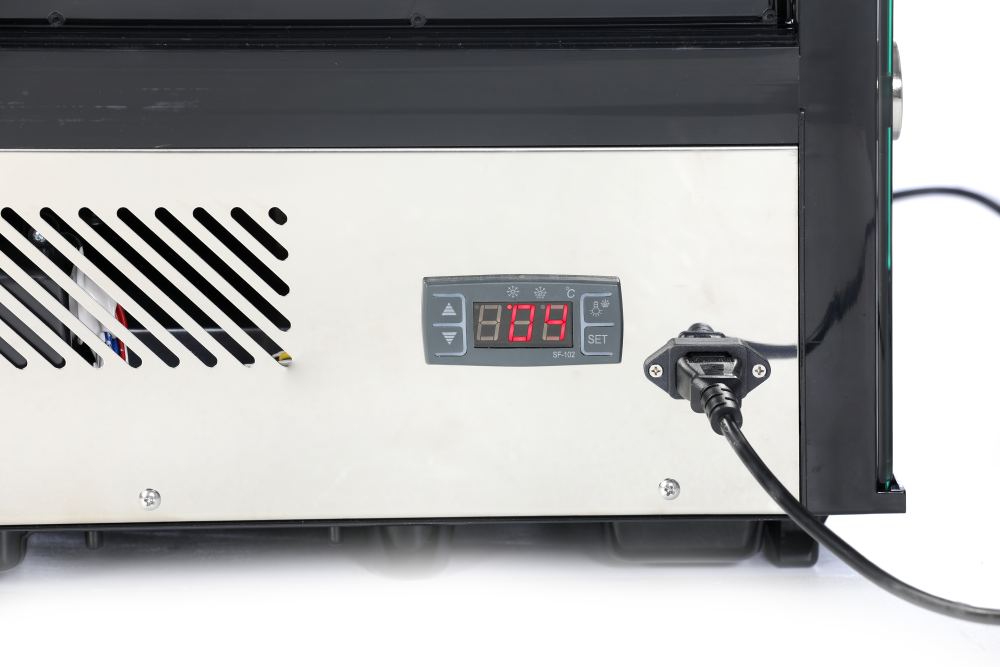 KBS Kühlvitrine, Nahansicht der unteren Gerätevorderseite mit Temperaturanzeige bei 4 &deg;C. Sichtbare Stromzufuhr. Edelstahlgehäuse mit Belüftungsschlitzen. Für gekühlte Snackauslagen.