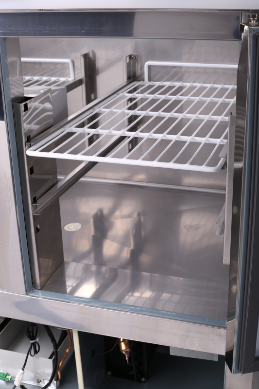 KBS Kühltisch Serie KTM 200/300 mit geöffneter Tür. Sicht auf Innenraum mit Drahtregal und seitlicher Belüftung &ndash; ideal für Kühlung in der Gastronomie.